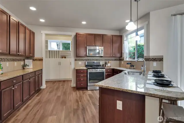 A wonderful kitchen boasts of rich wood cabinetry, granite counter tops with complementing custom tile backsplash.