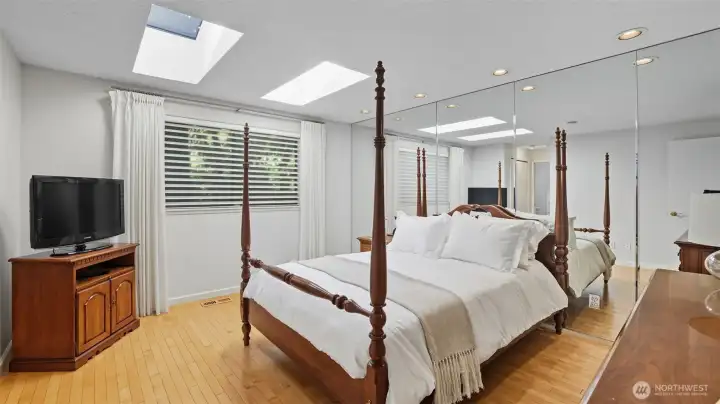 Spacious primary suite filled with natural light from skylights and large windows.