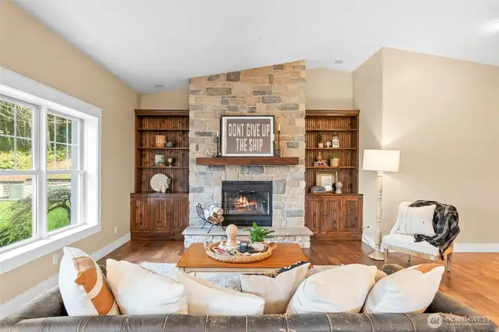 The hub of this home is the large living room off the kitchen featuring a stone fireplace, wood floors, solid wood built-ins, and vaulted ceilings.