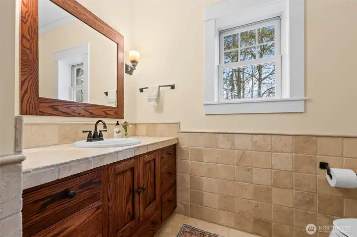 Main floor full bath with natural wood cabinetry and tile surrounds.