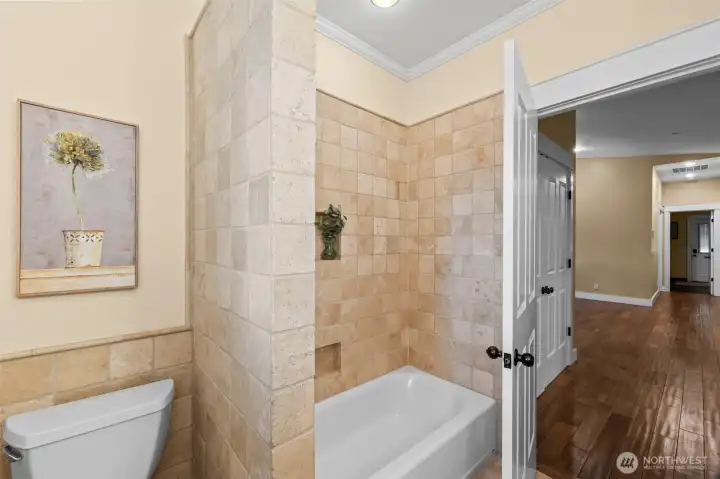 Main floor full bath with natural wood cabinetry and tile surrounds.