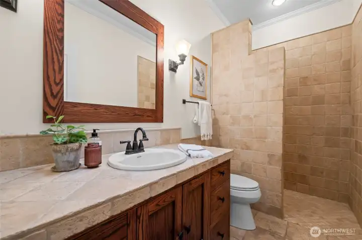 Private master .75 bath with natural wood cabinets and tile surrounds.