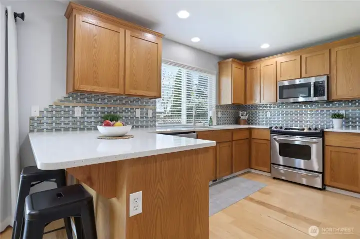 Eat-in bar counter provides wonderful connection to main living space, and easy conversation spot. Tile backsplash ties in the subtle colors and adds a stylish element.