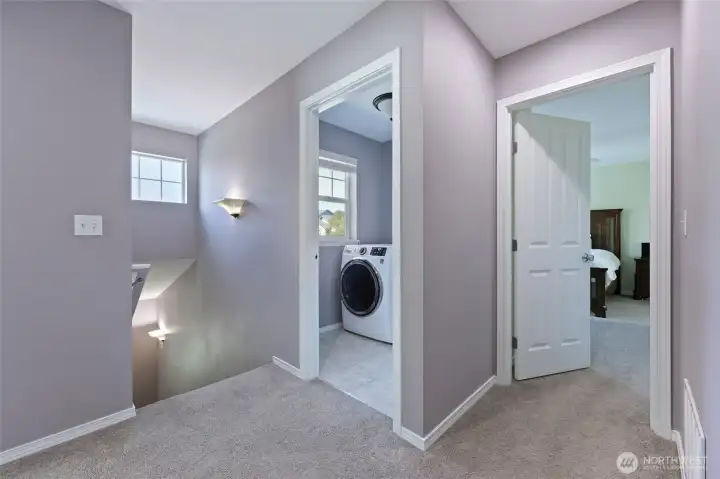 Roomy landing at the top of the stairs leads to beds/bath, laundry, and primary bedroom, seen here.