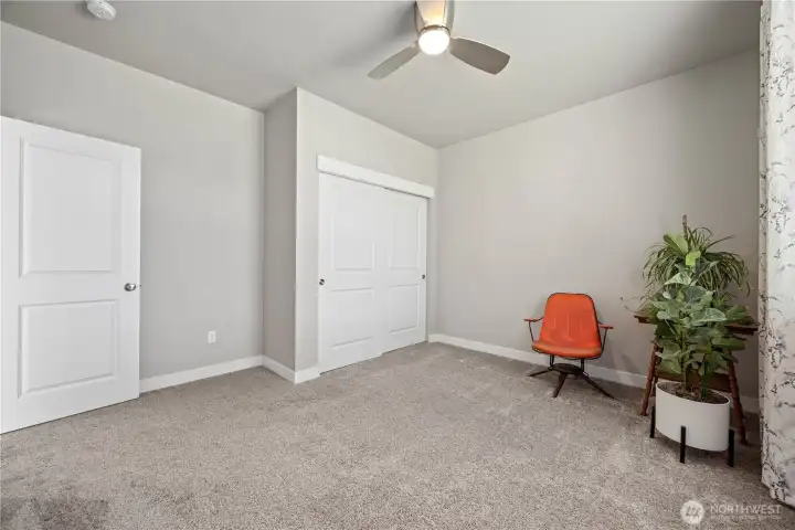 Front bedroom with upgraded fan, organized closet system, and beautiful natural light overlooking the peaceful neighborhood street.