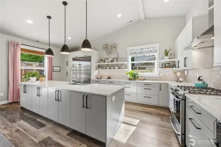 Designer kitchen showcasing quartz counters, automatic blind, open shelving, propane range, and expansive island in a stunning entertaining space.
