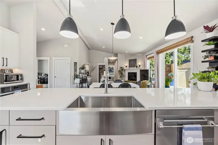 Massive 11.5-foot quartz island with farmhouse sink, extensive cabinetry on both sides, pendant lighting, and ample prep space.