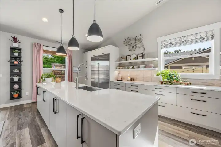 High-end kitchen centered around premium Sub-Zero refrigerator/freezer, custom cabinetry, quartz counters, and thoughtfully designed storage throughout.