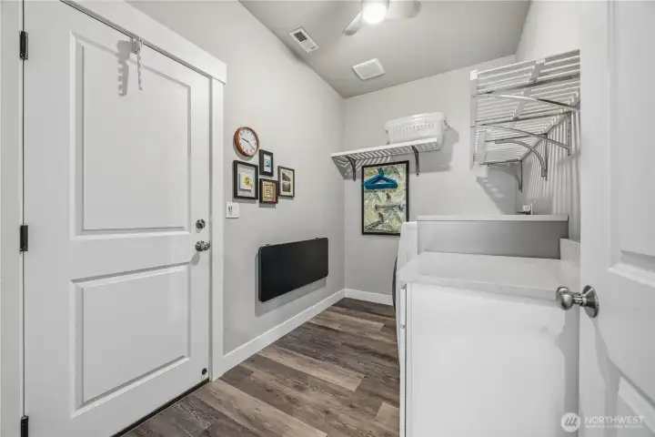 Functional laundry room with quartz folding counter, built-in storage, included appliances, and convenient access near the primary suite.