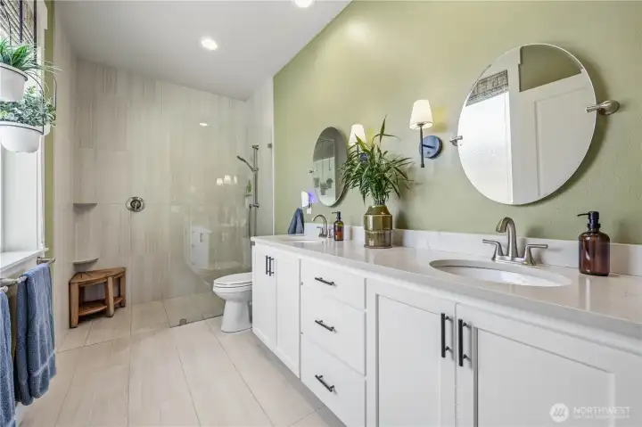 uxurious primary bathroom featuring heated floors, double sinks, quartz counters, and zero-clearance glass walk-in shower.