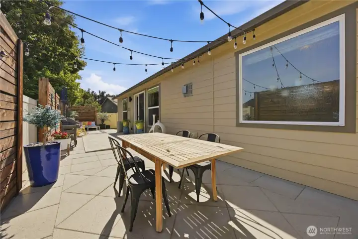 Charming outdoor entertaining area featuring party lighting, LED accent fencing, fire pit area, and inviting evening ambiance.