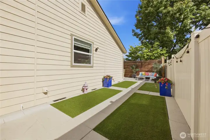 Spacious backyard with premium artificial grass, privacy fencing, gates on both sides, and room to relax or entertain.