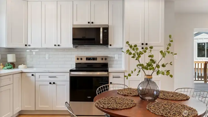 Kitchen has quartz counters, tile backsplash and lots of cabinetry.