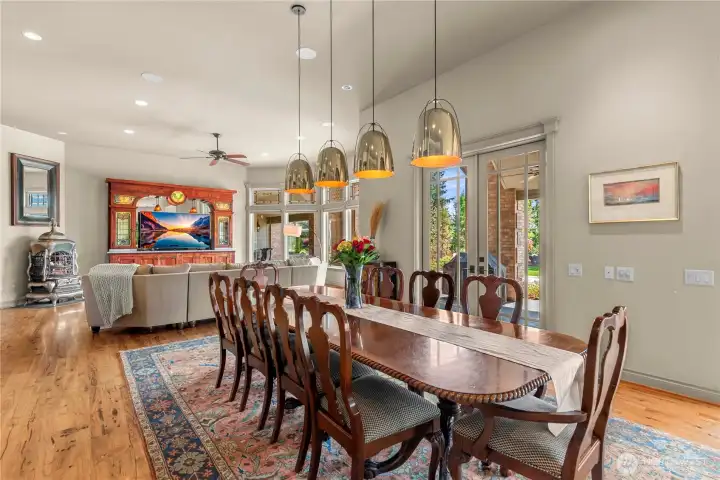 Open dining area highlighted by rich hardwood flooring, striking pendant lighting, and French doors that extend the entertaining space to the patio.