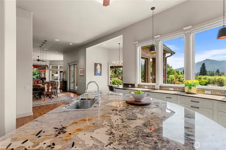 Open kitchen with a statement island and abundant counter space, designed to take in natural light and picturesque orchard and mountain views.