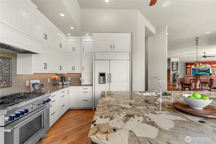 Beautifully appointed kitchen with custom cabinetry, high-end range, and a dramatic stone island offering generous prep space and seamless flow to the dining and living areas.