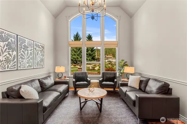 Sophisticated sitting area with soaring ceilings and a striking arched window that creates a light-filled space perfect for relaxing or entertaining.