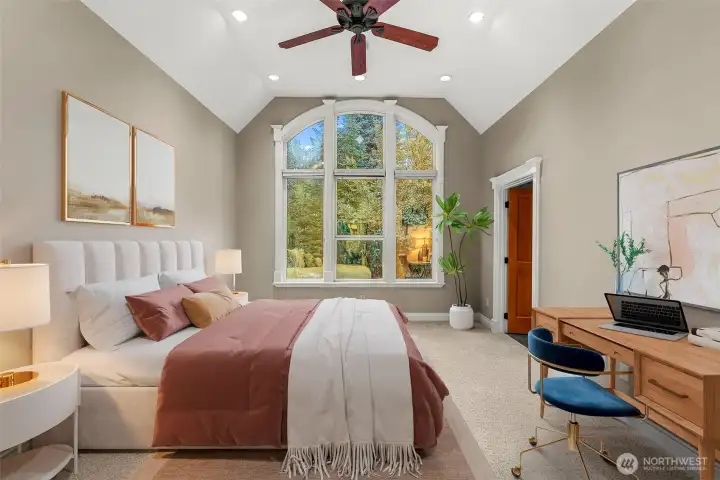 Light-filled guest suite featuring vaulted ceilings and a striking arched window that brings in beautiful natural light and views of the surrounding landscape