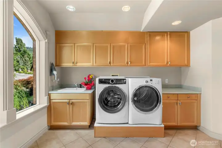 Spacious laundry room with extensive cabinetry, ample folding counter space, and a convenient utility sink.