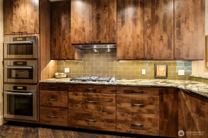 Premium Miele ovens are paired with a glass subway tile backsplash and under-cabinet lighting, creating both function and visual appeal.