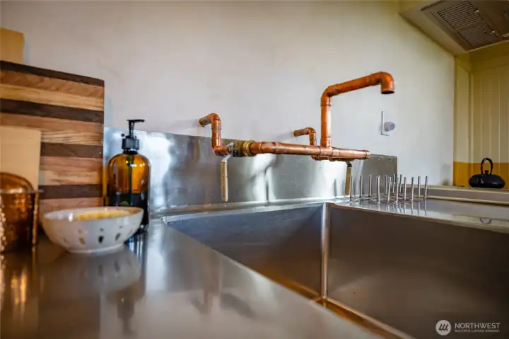 big farm sink with exposed copper piping.