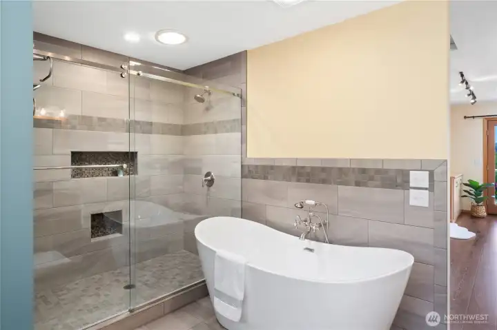 Primary bathroom w/ walk-in tiled shower and large soaking tub.