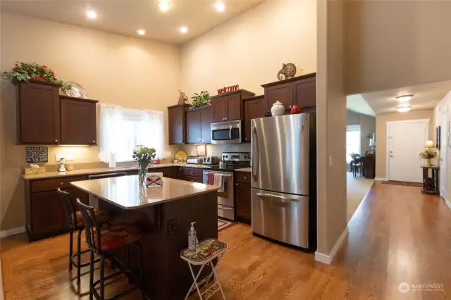 Well-planned kitchen with rich cabinetry, quartz counters, island with eating space, and stainless appliances.