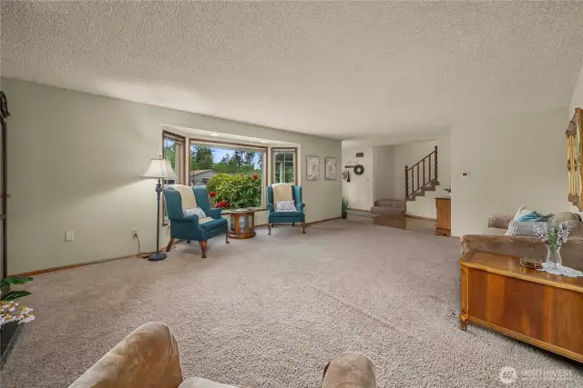 View of living room, entry, and stairs from dining room