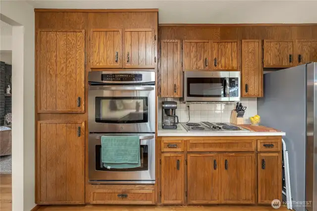 kitchen in it's original custom state with updated double ovens and microwave hood over the cook top