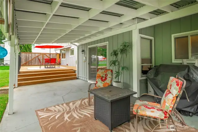 Covered patio with sliding door access to the lower living room and four steps up to large deck