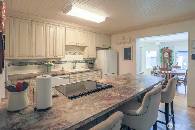 The updated kitchen features a brand-new stove installed in 2025.  Cabinets and countertops provide ample storage and workspace.  The seating area provides a great place to chat with the chef while they cook.