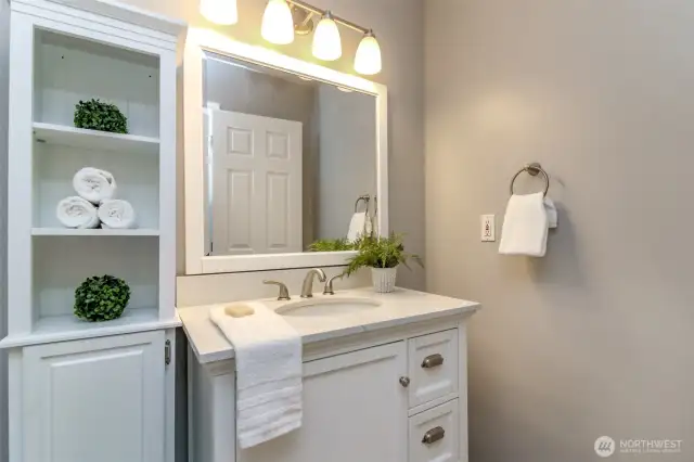 Primary bathroom with updated vanity, ceilings, flooring and storage cabinet.