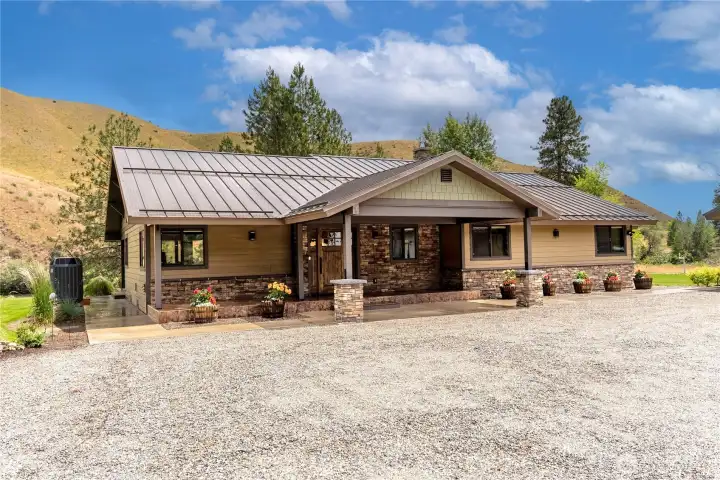 A beautifully designed exterior showcases timeless curb appeal with stone accents, a welcoming covered entry, and manicured flower beds. This home blends mountain charm with modern style in a picture-perfect setting.