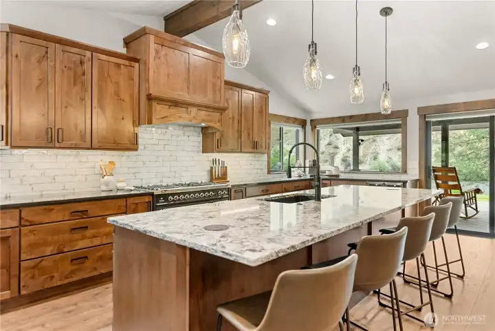 This stunning kitchen offers an open-concept design with custom wood cabinetry, quartzite countertops, and premium stainless steel appliances, creating both beauty and functionality.