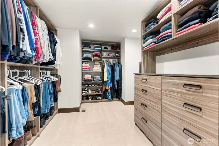 The spacious walk-in closet is designed for optimal storage and organization, featuring custom-built shelving, drawers, and hanging space. Neutral tones and clean lines give the space a modern feel, while abundant open shelving keeps clothing and accessories neatly displayed. The closet is both functional and elegant, offering plenty of room for a well-organized wardrobe.