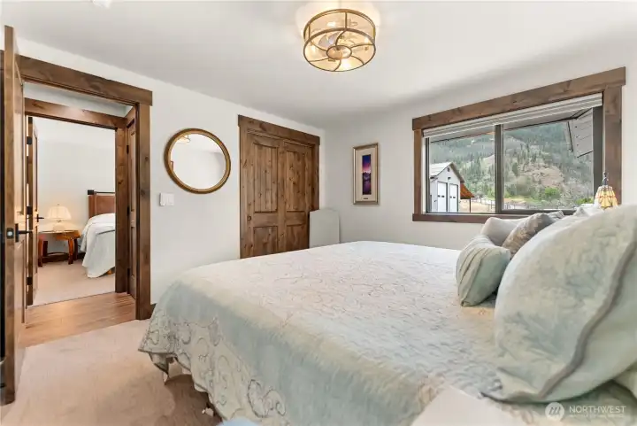 Wake up to breathtaking mountain views from this bright and inviting bedroom. A large picture window frames the natural scenery, while neutral tones and wood accents create a serene retreat.