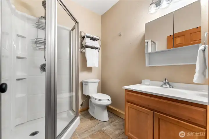 This guest bath features a spacious walk-in shower with glass enclosure, modern fixtures, and a sleek vanity with ample storage. Neutral tones and natural finishes create a bright and functional space.