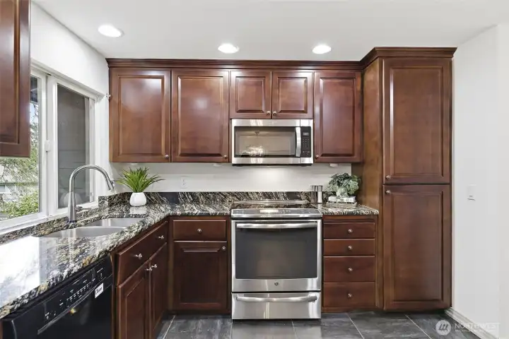 An open kitchen with slab granite counters and stainless appliances.