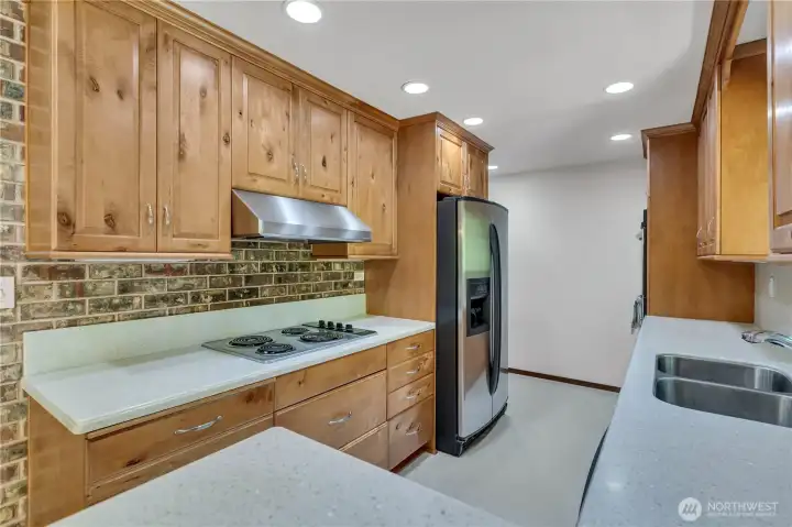 Upgraded kitchen with gorgeous warm wood cabinetry, corian counters with drop in sink, double oven and views of the backyard and swiming pool!