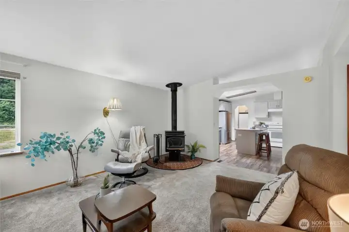 A view of the wood burning stove in the family room, with the kitchen beyond. A view of the wood burning stove in the family room, with the kitchen beyond.