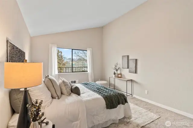 Another view of the spacious bedroom with a window that looks out over the balcony.