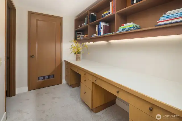 Built-in desk and bookshelves. Beyond the door, deep storage and utilities.
