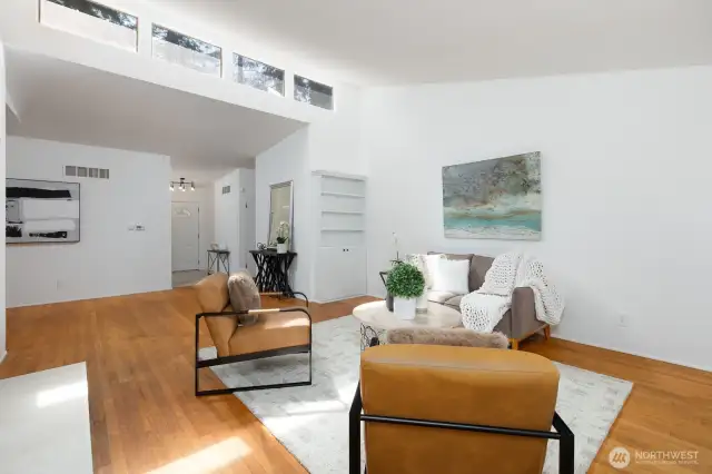 LIVING AREA LOOKING TOWARDS ENTRY WITH TALL CEILINGS AND UPPER WINDOWS GIVING THE SPACE EVEN MORE NATURAL LIGHT
