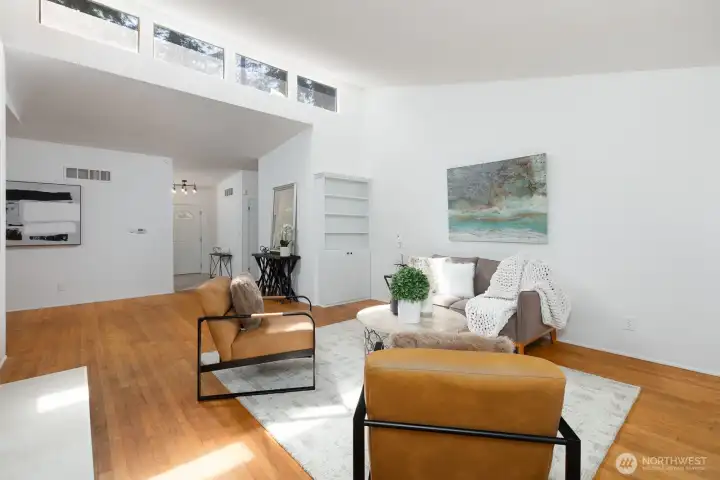 LIVING AREA LOOKING TOWARDS ENTRY WITH TALL CEILINGS AND UPPER WINDOWS GIVING THE SPACE EVEN MORE NATURAL LIGHT