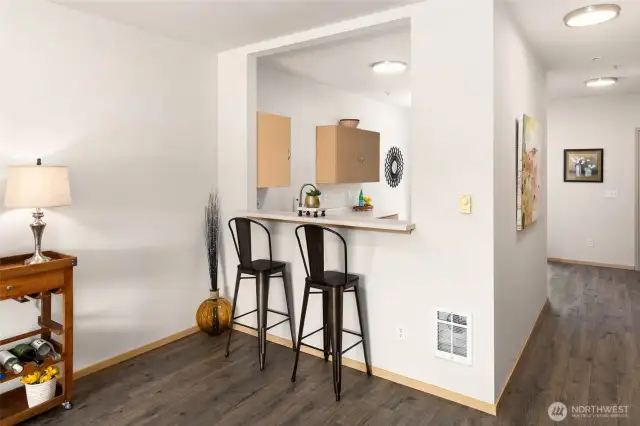 Dining room shows kitchen bar counter and new easy care, premium laminate flooring throughout the main level