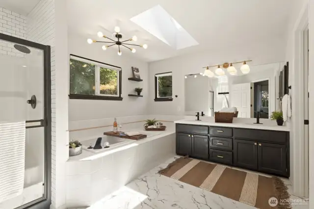 The expansive primary bathroom includes a separate shower, soaking tub, double vanity, toilet room and skylight.
