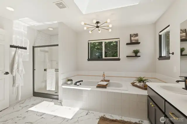 The recently updated, modern primary bath has gorgeous new tile flooring and a skylight to provide plenty of natural light.