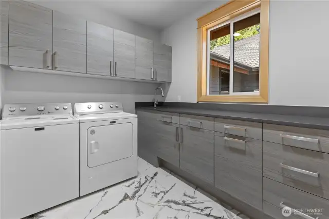 Laundry room on 2nd floor with tons of drawers and cabinets plus a sink and built-in trash can.