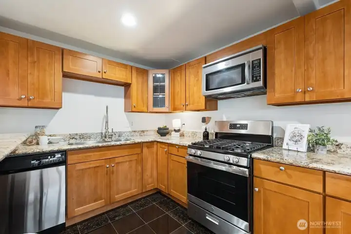 Upgraded kitchen with wood cabinets, granite countertops, and stainless steel appliances, including gas cooking