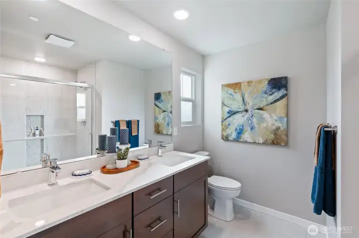 Primary Bathrooms with quartz counter tops, dual sinks,  tile floors and full title showers with beautifully curated title accents. Photos are of model home in the community.
